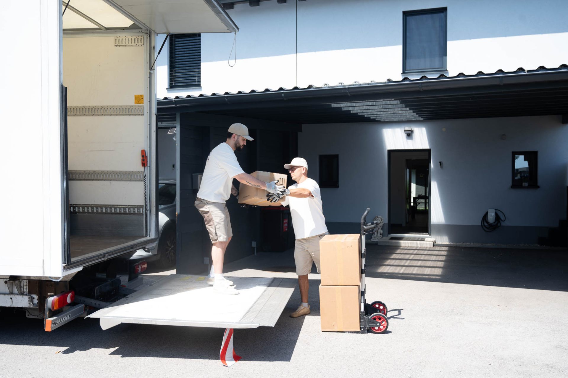 Kudera Mitarbeiter tragen Möbel über die Hebebühne in den LKW